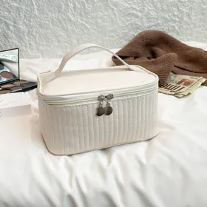 Detailed view of cream quilted PU leather cosmetic bag with sturdy top handle