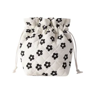 Detailed view of white quilted drawstring bag with black floral pattern design