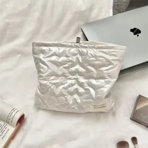 White quilted PU cosmetic bag with heart pattern on white fabric with lifestyle props