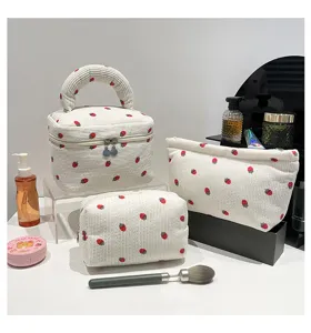 Detailed shot of white corduroy cosmetic bag set featuring a cute red strawberry print design