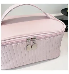 Close-up of pink PU leather makeup bag with vertical stitching and dual metal zippers.