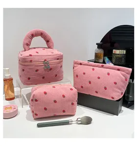 Close-up of pink corduroy cosmetic bag set featuring cute strawberry prints and handle