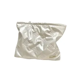 Iridescent white quilted PU cosmetic bag featuring embossed bow patterns for makeup storage