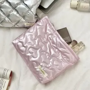 Pink quilted heart cosmetic bag and organizer with metallic finish in a flat lay