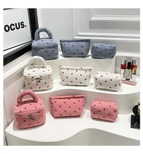 Collection of corduroy travel organizer bags with strawberry prints on display stand