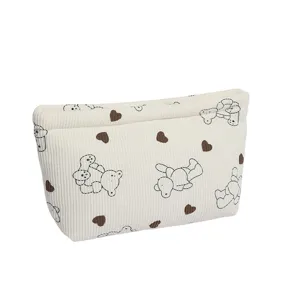 Macro detail of a corduroy cosmetic bag featuring a cute teddy bear and heart pattern print.