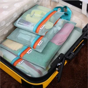 Detailed view of green mesh packing cubes set neatly organized in a yellow suitcase