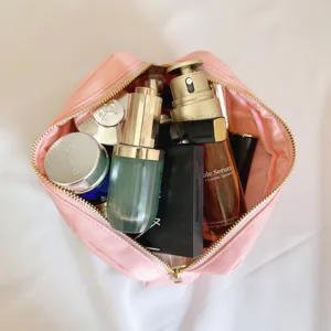 Détail d'une trousse de maquillage rose en nylon montrant sa grande capacité de rangement