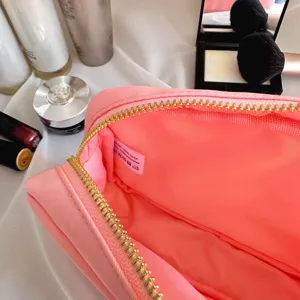 Détail de l'intérieur d'une trousse de maquillage rose en nylon avec fermeture éclair