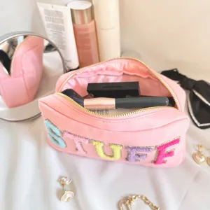 Vue détaillée d'une trousse de maquillage en nylon rose avec broderie STUFF