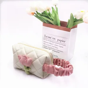 Macro view of corduroy cosmetic bag with pink tulip applique and ruffled handle.