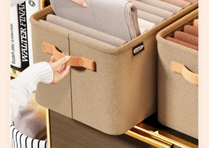 Close-up of beige fabric storage bin with durable orange handle for closet organization.