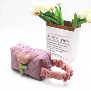 Close-up of pink corduroy makeup bag featuring tulip decor and a soft ruffled handle