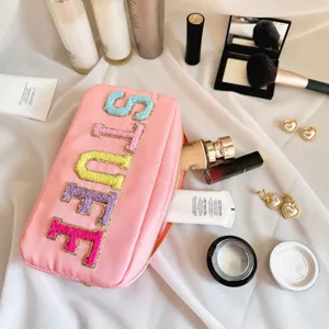 Gros plan d'une trousse de maquillage en nylon rose avec broderie de lettres 'STUFF'