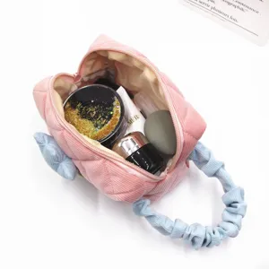 Detail view of a pink corduroy makeup bag with tulip decoration and blue ruffled handle