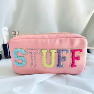 Gros plan détaillé d'une trousse de maquillage en nylon rose avec patchs STUFF
