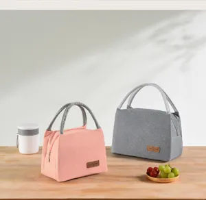 Detail view of pink and grey Oxford cloth insulated lunch bags on a wooden table