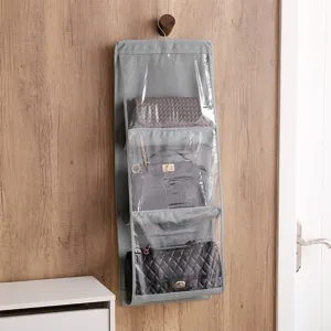 Grey 3-pocket hanging handbag organizer showing three luxury purses inside a closet.