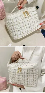 Close-up of elegant white tweed makeup bag with gold thread and dual zippers.