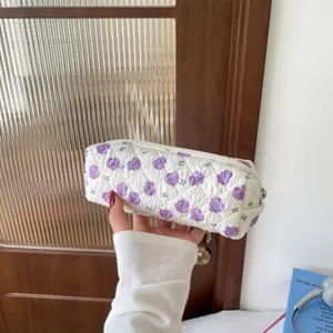 Detailed view of white quilted pencil case with purple floral pattern and zipper