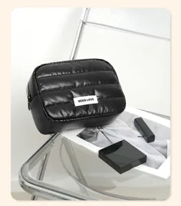 Detailed view of a black puffer quilted cosmetic storage bag featuring a Been Love label
