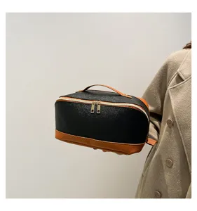 Detaillierte Handansicht der großen schwarz-braunen Kosmetiktasche aus PU-Leder