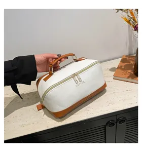 Nahaufnahme der weiß-braunen PU-Leder Kosmetiktasche mit Simpler-Logo und Griff