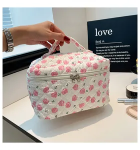 Detail view showing quilted cotton cosmetic bag with pink floral print and zipper closure.