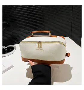 Detailansicht einer weißen PU-Kosmetiktasche mit braunem Lederbesatz und Tragegriff