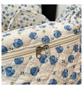 Close-up of quilted cotton cosmetic bag with blue rose pattern and double zippers