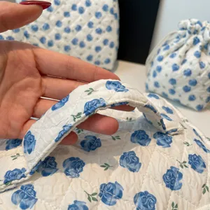 Detail view of quilted cotton cosmetic bag handle featuring elegant blue floral rose pattern