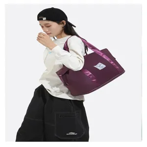 Grand sac de voyage violet étanche et pliable pour fitness porté par un mannequin asiatique