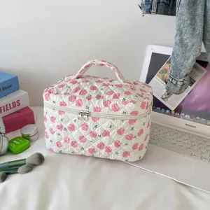Floral quilted cosmetic bag displayed on a desktop with makeup brushes and a laptop