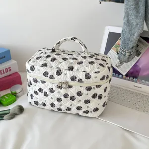 Close-up of the white quilted cosmetic bag with black rose patterns in a travel setting