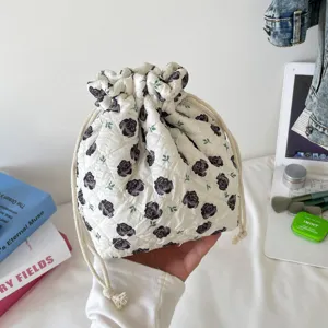 Detailed view of white quilted drawstring cosmetic bag with elegant black rose print