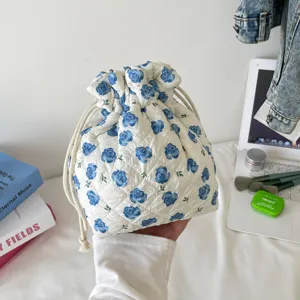 Detailed view of a quilted cotton drawstring cosmetic bag featuring blue rose floral patterns.
