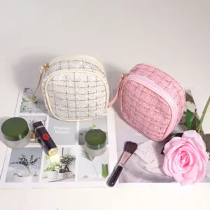 Vue détaillée d'élégantes trousses à maquillage en tweed rose et crème avec fils d'or