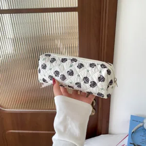 Close-up of a quilted floral pencil case with black rose patterns in hand