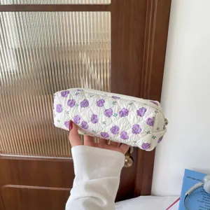 Detailed view of quilted cotton cosmetic bag featuring purple floral patterns and zipper