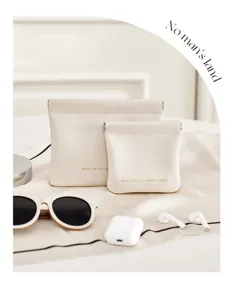 Détail de pochettes en cuir crème pour organiser des accessoires technologiques.