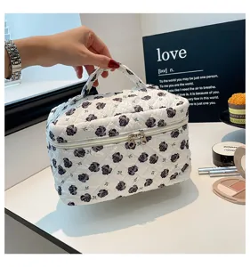 Close-up of a handheld quilted cotton makeup bag featuring a black rose floral pattern