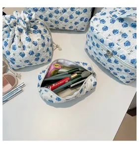 Detailed view of an open quilted floral cosmetic bag filled with various makeup tools