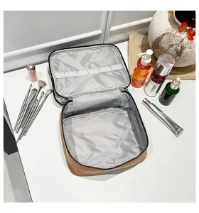 Vista dettagliata che mostra gli ampi scomparti interni grigi della borsa per il trucco marrone.