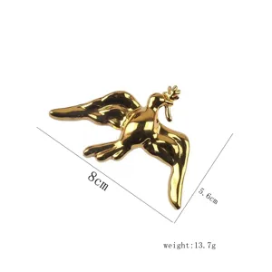 Vista detallada del broche de paloma de la paz en acero dorado con medidas 8cm x 5.6cm