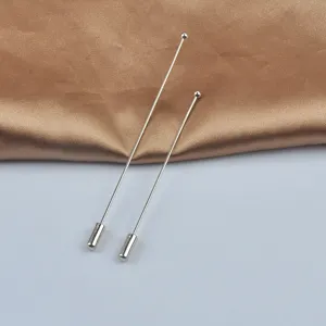 Detailansicht von zwei minimalistischen silbernen Rundkopf-Anstecknadeln auf Seide