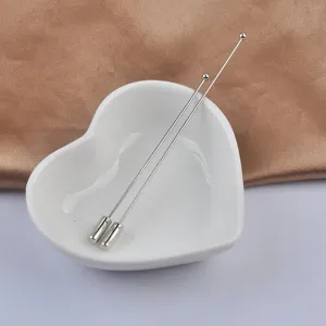 Nahaufnahme von minimalistischen silbernen Rundkopf-Anstecknadeln in Herzschale