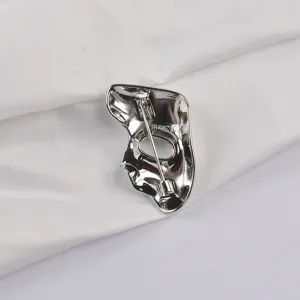 Detailed macro view showing the back pin mechanism of the silver mask brooch.