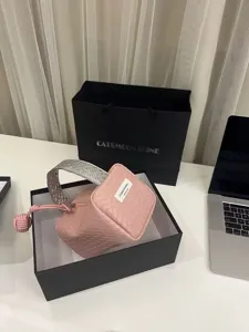 Detailansicht der rosa-silber gewebten Kosmetiktasche in einer schwarzen Geschenkbox