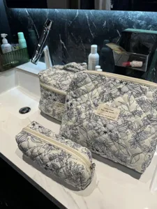 Three floral quilted cotton cosmetic bags set on a white marble bathroom vanity.
