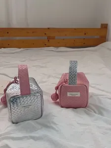Nahaufnahme von handgefertigten Make-up-Taschen mit Webmuster in Silber und Rosa